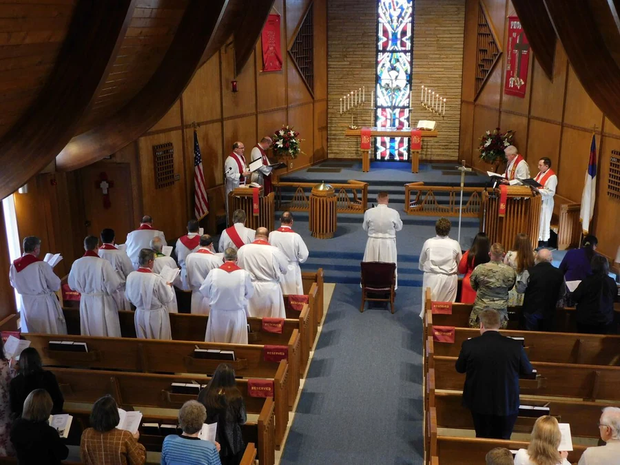 The congregation gathered for a service in Faith Lutheran's timber sanctuary, facing the altar and tall stained-glass window.